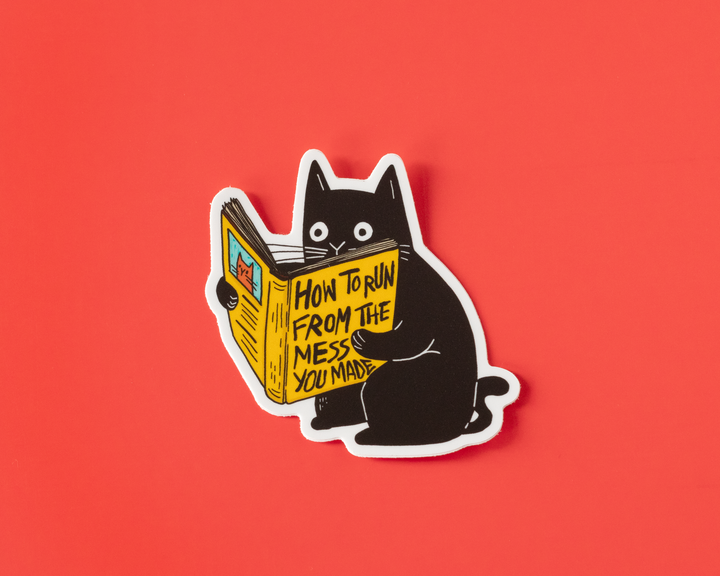 Sticker of a black cat reading a book titled &